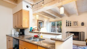 Una cocina con armarios de madera, encimeras de granito, lavavajillas y chimenea.