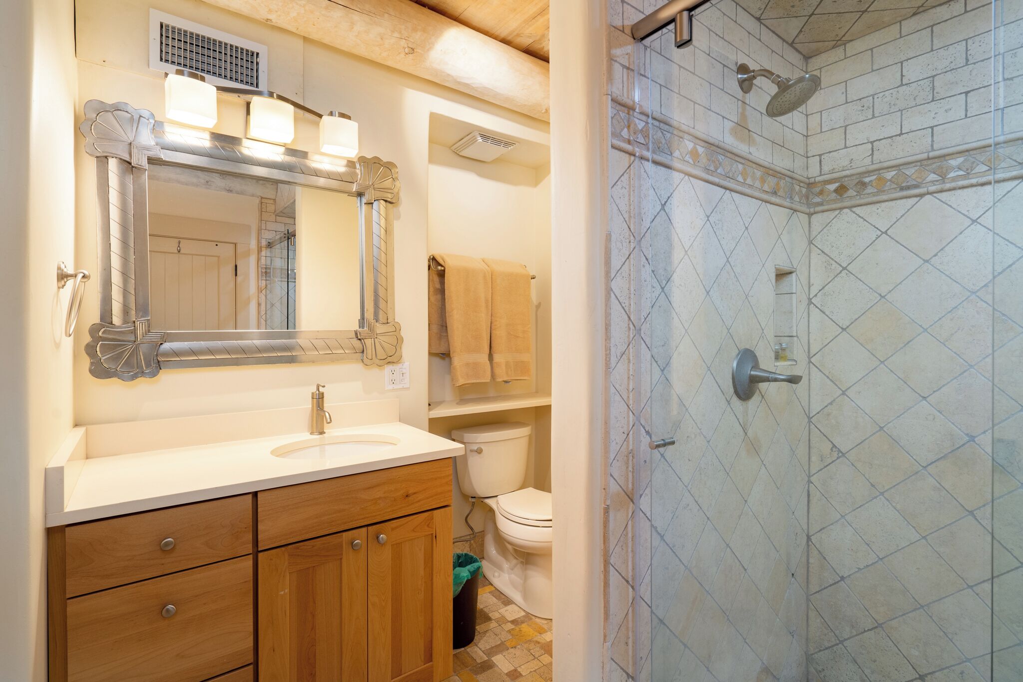 Un bagno con un mobile lavabo in legno, uno specchio grande, un water e una cabina doccia con pareti piastrellate.