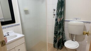 A bathroom with a glass shower enclosure, a toilet, and a sink. - Tumby Bay Motel (Tumby Bay)