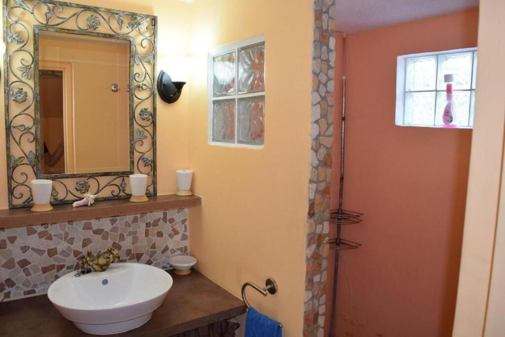 A bathroom with a large mirror, a sink, a toilet, and a shower area.