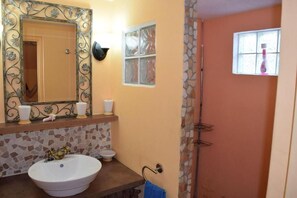 Une salle de bain avec un grand miroir, un lavabo, des toilettes et un espace douche.