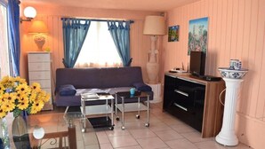 Een gezellige woonkamer met een bank, een salontafel, een televisie en een eethoek met een tafel en stoelen.