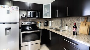 Una cocina moderna con electrodomésticos de acero inoxidable, encimera de granito y armarios negros.