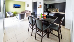 A modern kitchen with dark cabinets, a granite countertop, and a dining area with a black table and four chairs.