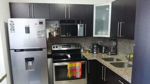 A modern kitchen with stainless steel appliances, granite countertops, and dark cabinetry.