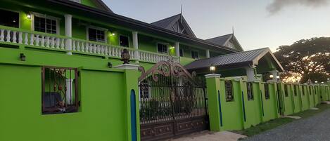 A large, green house with a white balcony and a decorative gate.