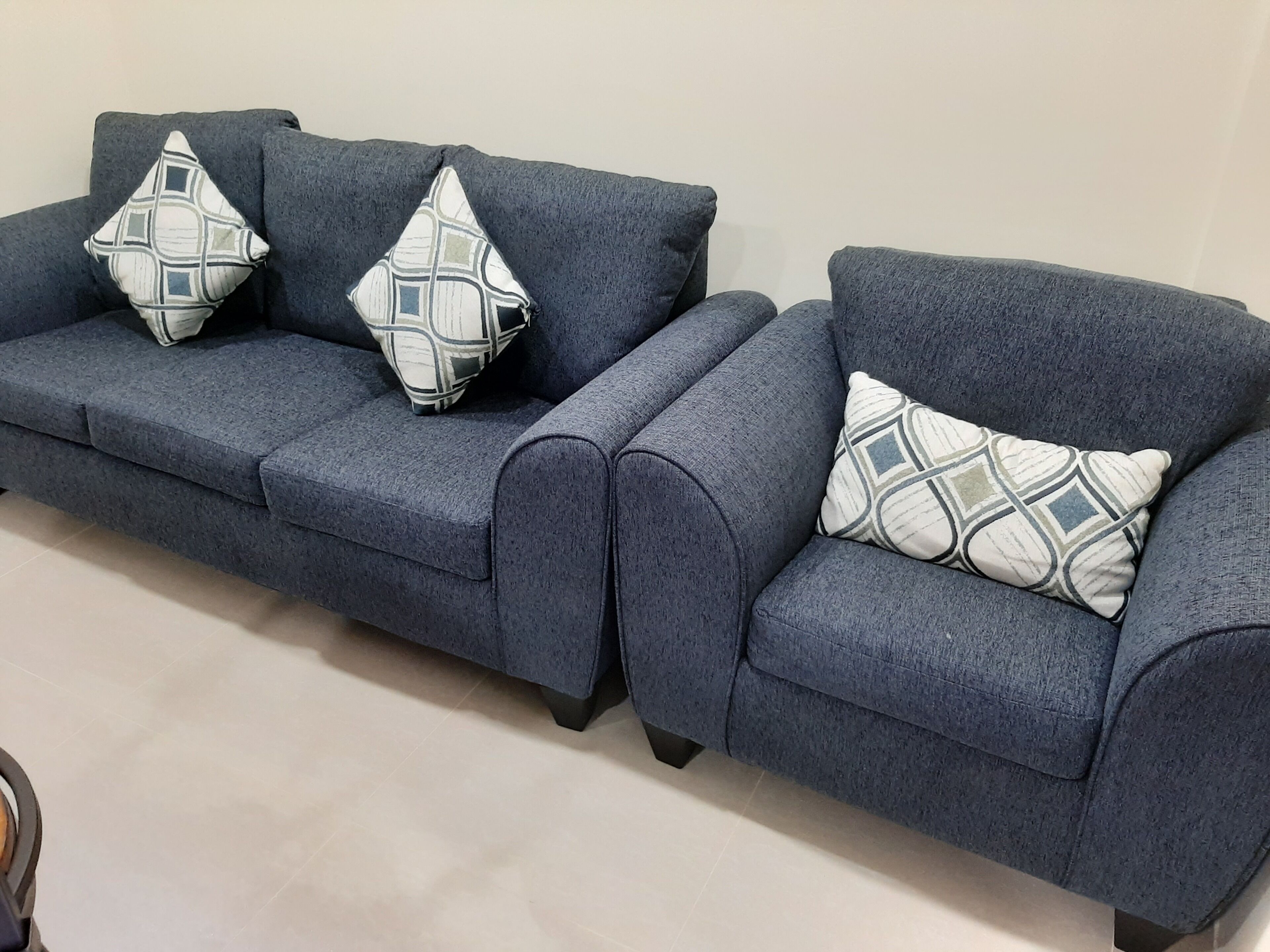A dark blue sofa with three patterned pillows.