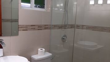 Une salle de bain moderne avec une douche à parois de verre, un lavabo blanc et des toilettes.