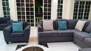 A living room with a grey sofa set, two armchairs, and a patterned rug.