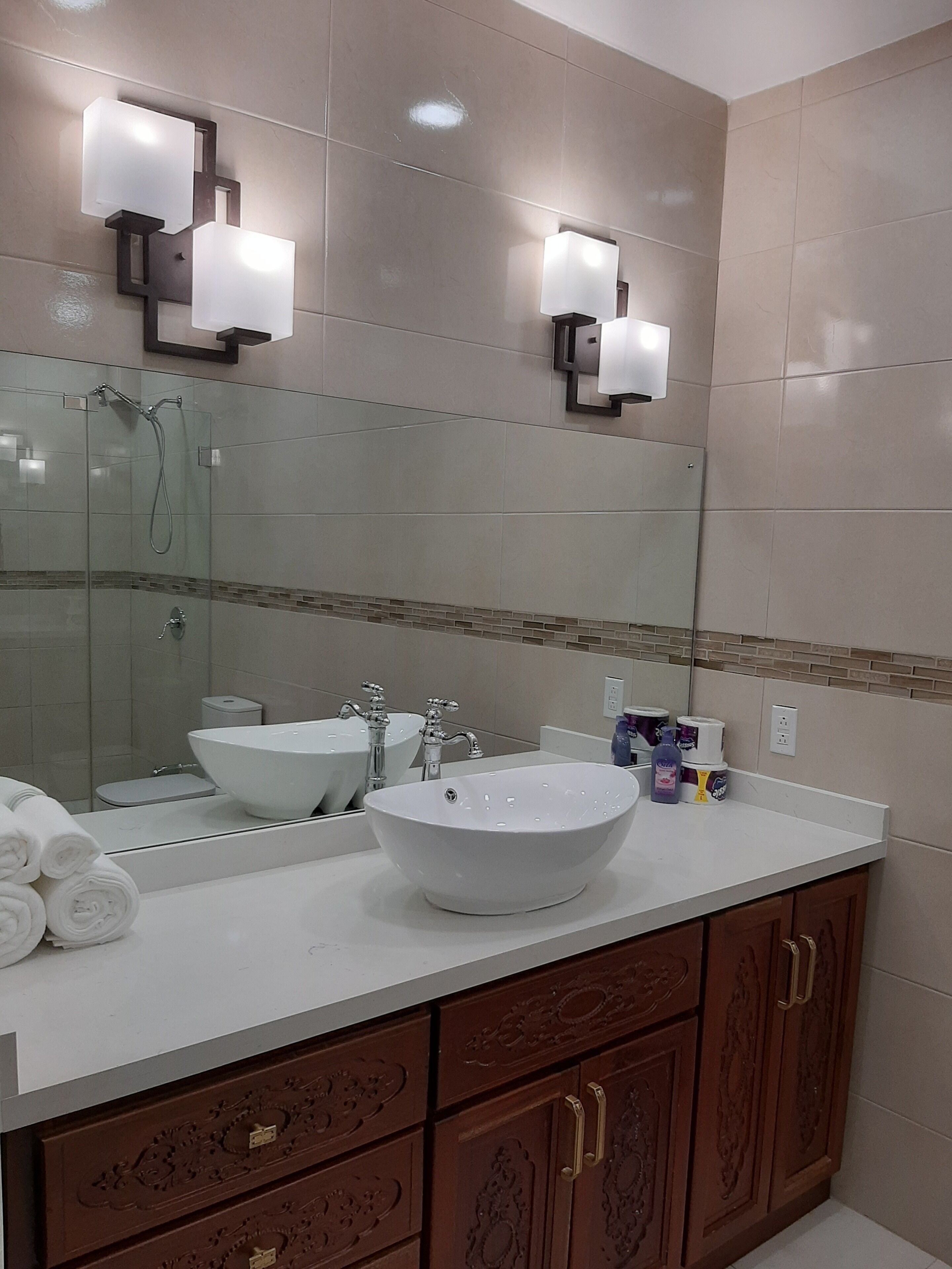 Une salle de bain avec un grand miroir, deux lavabos, une douche et un porte-serviettes.