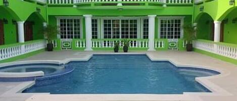 A large, two-story building with a central courtyard featuring a swimming pool.