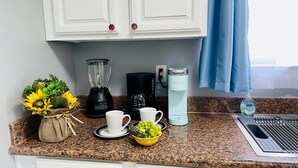 Eine Küchenarbeitsplatte mit Kaffeemaschine, Mixer, Wasserkocher und Spüle.