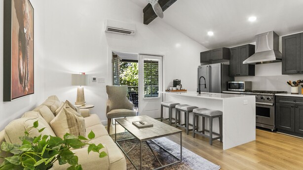 A modern kitchen with a central island, bar stools, and a ceiling fan.