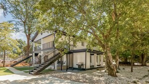 A two-story house with a covered patio, a staircase, and a small outdoor seating area.
