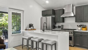 A modern kitchen with a central island, stainless steel appliances, and dark cabinetry.