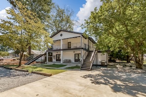 A two-story house with a covered porch, a staircase, and a small shed.