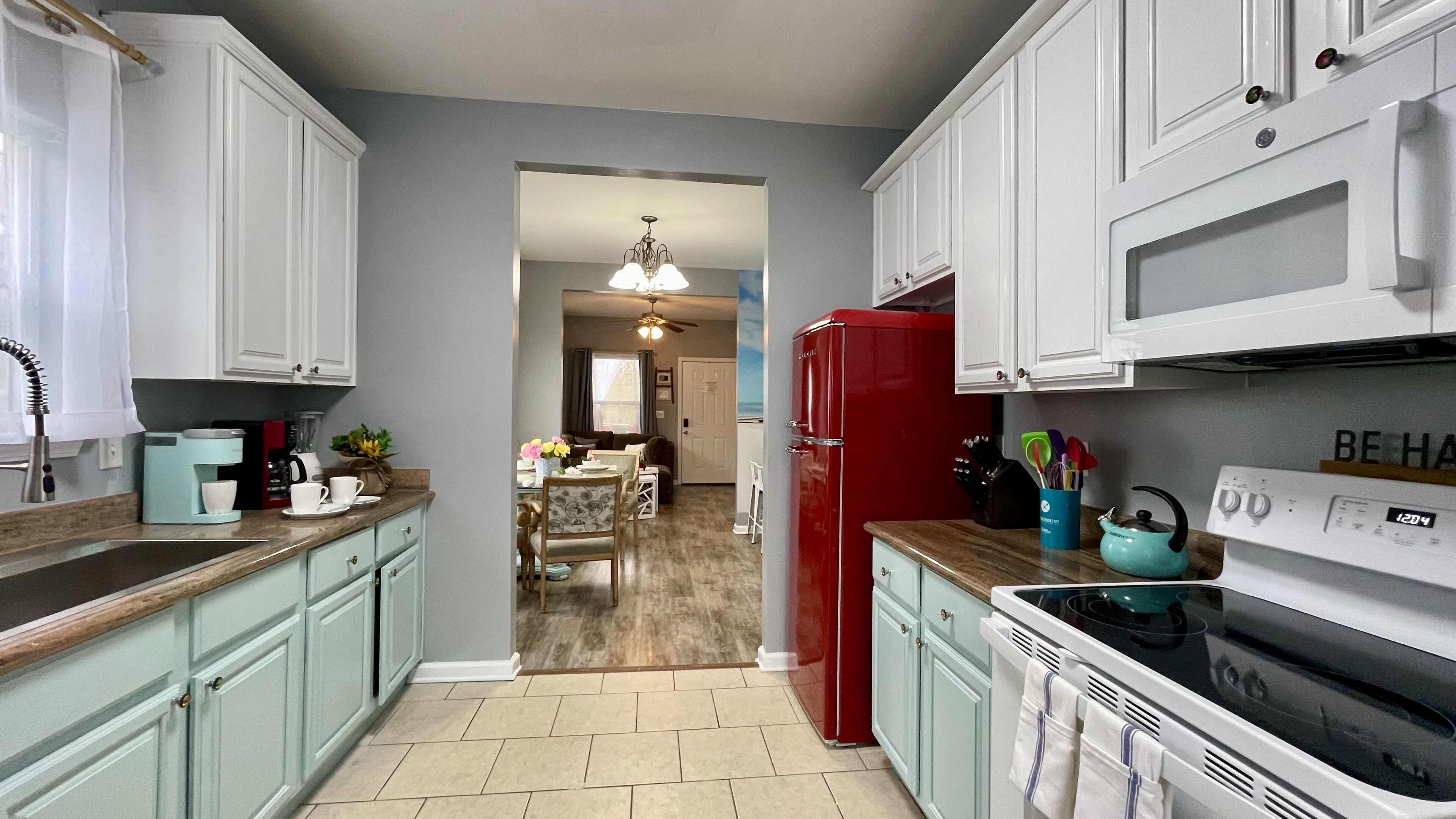 A kitchen with light blue cabinets, a red refrigerator, and a white stove.