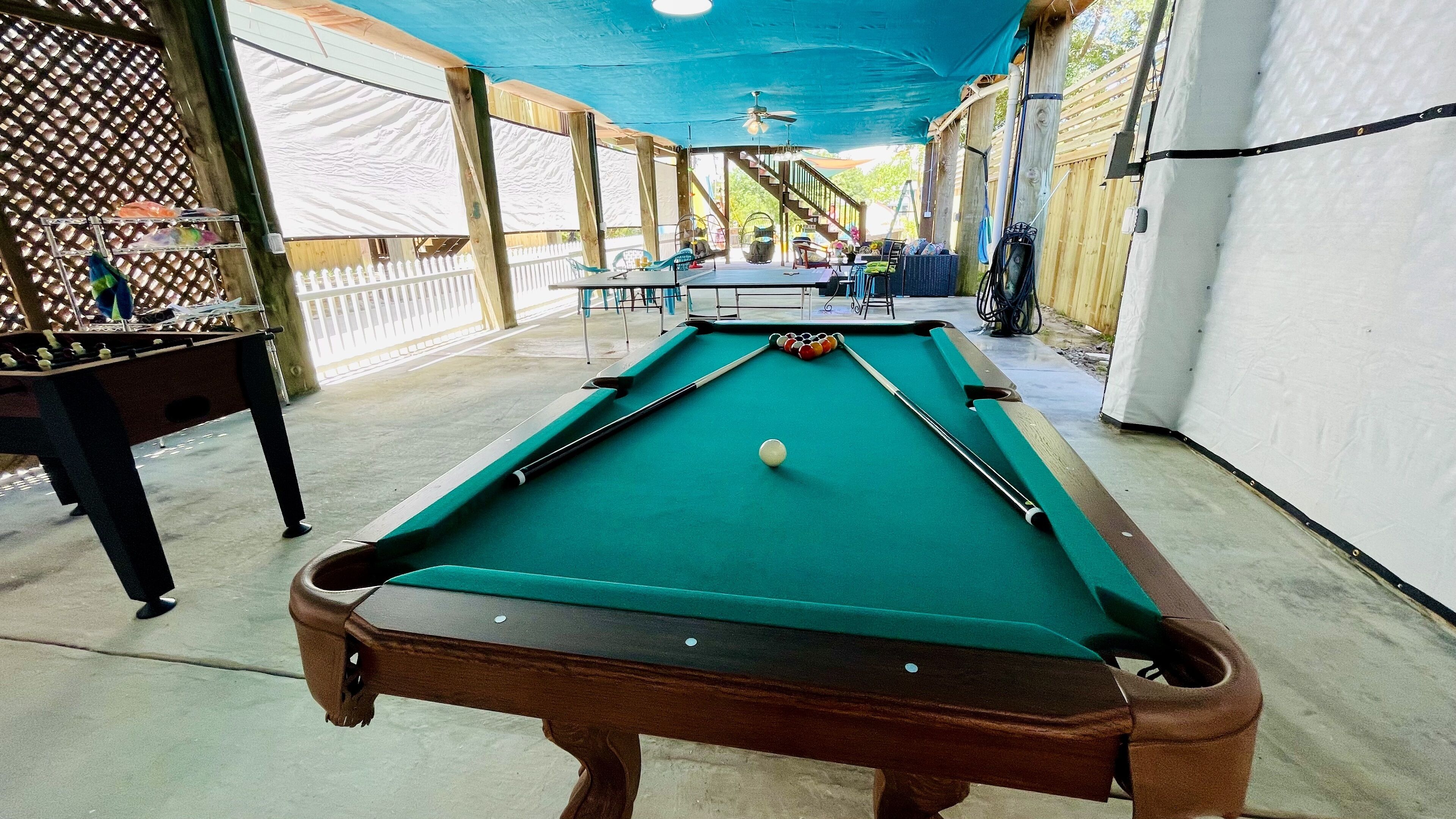 A pool table with a green felt surface, a white cue ball, and several pool cues.