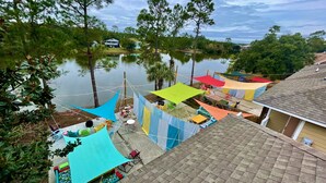 Una zona residencial con un estanque, casas y un patio con toldos de colores.