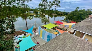 A residential area with a pond, houses, and a patio with colorful canopies.