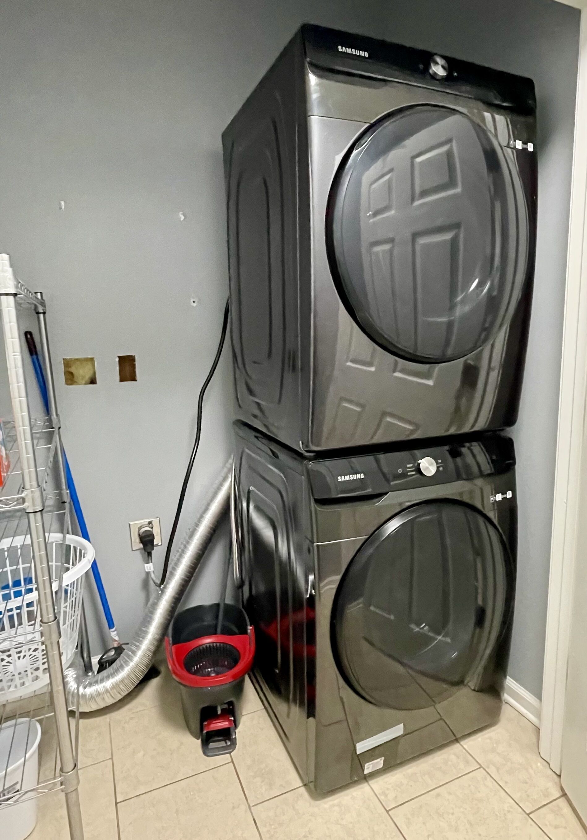 A stacked washer and dryer unit with a hose connected to the bottom unit.