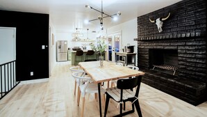 A modern kitchen with a black brick fireplace, a wooden dining table, and white chairs. - Lake Front Paradise, Pool and Hot Tub-Bubbly (Mesa)