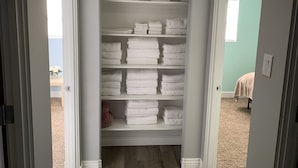 Ein begehbarer Kleiderschrank mit mehreren Regalen voller ordentlich gefalteter weißer Handtücher.