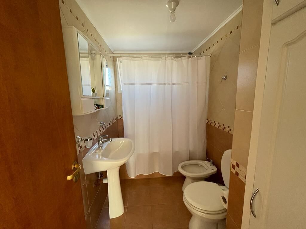 Un baño con lavamanos, inodoro y cortina de ducha.
