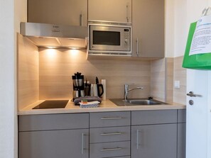 Cocina compacta con microondas, pileta y muebles de acero inoxidable.