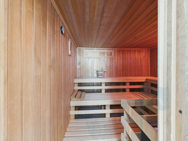 A sauna with wooden benches and a wooden wall.