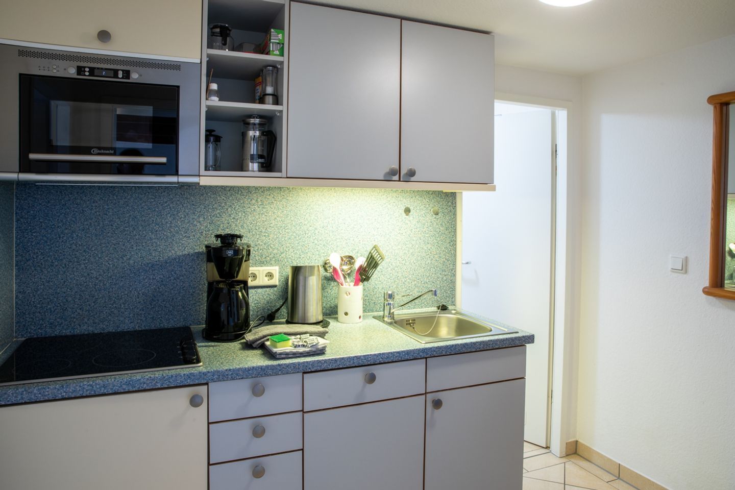 Eine Küche mit Backofen, Kaffeemaschine, Spüle und Schränken.