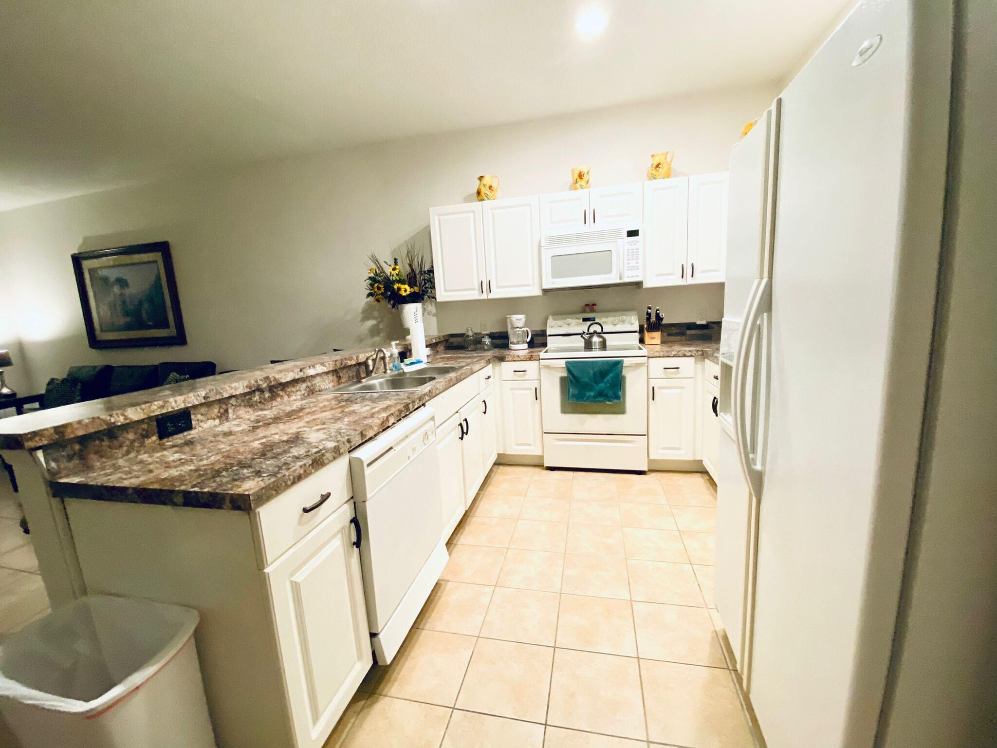 A kitchen with white cabinets, a granite countertop, a stove, and a microwave.
