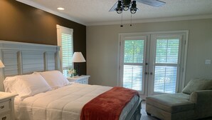 A bedroom with a bed, nightstands, a chair, and a ceiling fan.