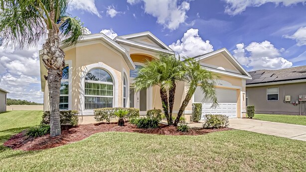 A single-story house with a large front window, a garage, and a well-maintained lawn. - Gated Community, Private Pool and Game Room Near Disney!!! (Kissimmee)