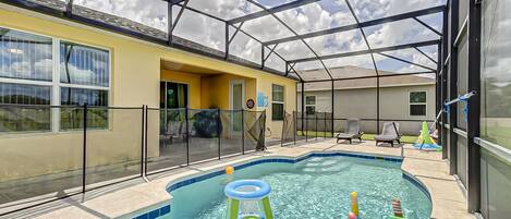 An indoor swimming pool with a glass ceiling, surrounded by lounge chairs and a yellow building.