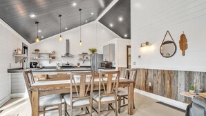 A modern kitchen with wooden dining table and chairs, built-in appliances, and pendant lighting. - Boyne City- close to golf, lakes, shopping and more!!!  (Boyne City)