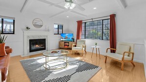 Una sala de estar moderna con chimenea, televisor, sofá, mesa de centro y ventilador de techo.
