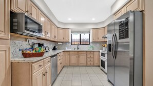 Una cocina moderna con armarios de madera, electrodomésticos de acero inoxidable y encimera de granito.
