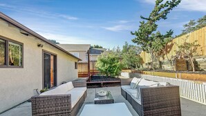 Un patio al aire libre con mobiliario de mimbre, una chimenea y vistas del barrio circundante.