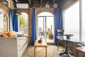 Relax in this inviting space with a comfortable sofa, wooden table, and stunning views of the outdoors through large windows.