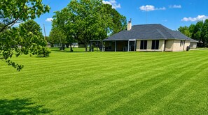 A house with a well-maintained lawn, a covered porch, and a chimney.