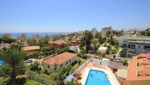 A residential area with a swimming pool, surrounded by houses and palm trees, overlooking a coastal cityscape. - Stunning 1 bed apt Benalmadena (Benalmádena)