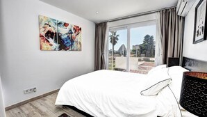 A modern bedroom with a large bed, a view of the outdoors, and abstract art on the wall. - Stunning 1 bed apt Benalmadena (Benalmádena)