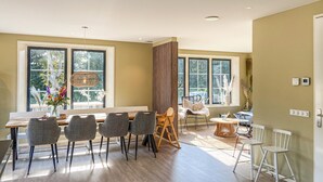 A modern dining area with a wooden table, grey upholstered chairs, and a large window with a view of greenery. - 5 bedroom awesome home in Groote Keeten (Groote Keeten)