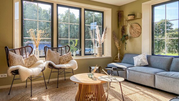 A cozy living room with a large window, a sofa, two chairs, a small table, and decorative items. - 5 bedroom awesome home in Groote Keeten (Groote Keeten)