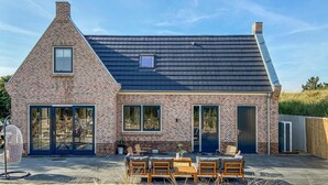 A brick house with a sloped roof, large windows, and a patio area with outdoor furniture. - 5 bedroom awesome home in Groote Keeten (Groote Keeten)