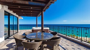 Ein Balkon mit Korbmöbeln, einem Whirlpool und Blick aufs Meer.