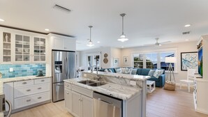 A modern kitchen with white cabinetry, a marble island, and stainless steel appliances. - Back To Blue: Amazing Bean Point Location, Resort Style Backyard with Pool by Anna Maria Life (Anna Maria)