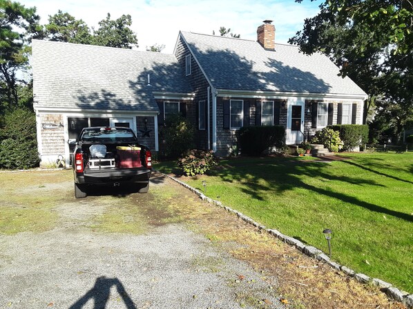 Stroll up to this charming home, featuring a front porch and a chimney, surrounded by lush lawns and mature trees.