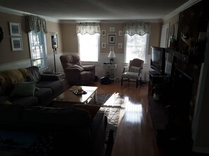 Cozy living room with a traditional layout, featuring a leather sofa, armchair, and fireplace.